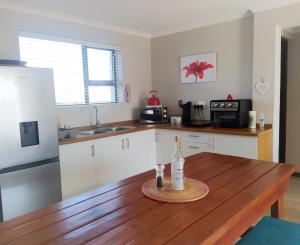 a kitchen with a wooden table with a bottle of wine at Alive@4 in Mossel Bay