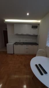 una cocina con armarios blancos, una mesa y una barra en Bistrik Studio, en Sarajevo