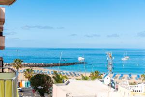 widok na plażę z krzesłami i łodziami w wodzie w obiekcie 17 LOS CRISTIANOS CENTRAL by the BEACH ,WiFi w Aronie