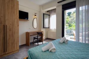 a bedroom with a bed and a desk and a television at Liotrivi Houses at Old Nikiti in Nikiti