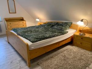 1 dormitorio con cama de madera y manta negra en Haus am Schilf en Nordstrand