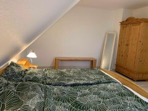 1 dormitorio con 1 cama con edredón verde en Haus am Schilf en Nordstrand