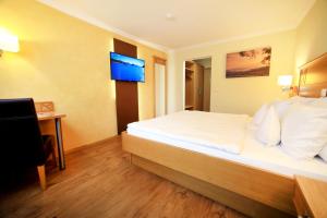 ein Hotelzimmer mit einem Bett und einem Fernseher in der Unterkunft Landidyll Hotel Restaurant Birkenhof in Klosterkumbd