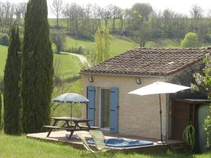 una casa con tavolo, sedie e ombrellone di Détente à Cordes-sur-ciel, vue magnifique, SPA a Souel-et-Sarmases