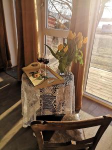 a table with a vase of flowers and two glasses of wine at Strandheimen Guesthouse in Melhus