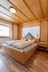 un letto grande in una stanza con soffitto in legno di Fernerblick Apartments a Tux
