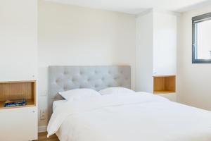 a white bedroom with a large white bed and a window at Regina's Banyuls - Modern and brand new apartment in Banyuls-sur-Mer
