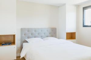 una camera da letto bianca con un grande letto bianco e una finestra di Regina's Banyuls - Modern and brand new apartment a Banyuls-sur-Mer