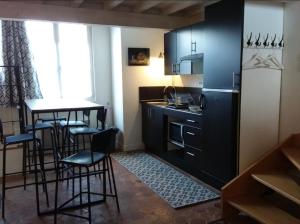 eine Küche mit einem schwarzen Kühlschrank und Barhockern in der Unterkunft Maison de village à Omerville in Omerville