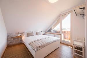 Dormitorio blanco con cama y ventana grande en GrosAlp apartments, en Lesce