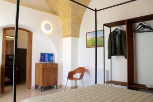 Caprarica di LecceにあるMasseria Rifisa AgriResortのベッドルーム1室(ベッド1台、椅子、鏡付)