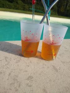 two cups of drinks sitting on a table next to a pool at Domaine de la Vaudourière in Lunay