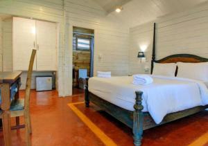 a bedroom with a large bed with a desk and a table at Lotus Feet Cottages, 100 Odd Meters from Morjim Beach in Morjim