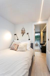 a bedroom with a white bed and a living room at Lemuria Houseboat - pływający domek na wodzie in Wrocław