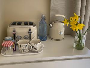a counter with cups and a toaster and flowers on it at Private Entry Double bedroom with beautiful views! in Solihull
