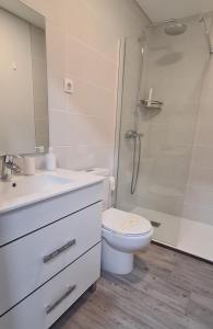 a white bathroom with a toilet and a shower at Casa Beira Rio in Viana do Castelo