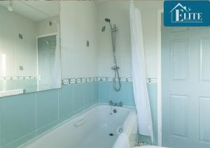 ein Bad mit einer Badewanne, einer Dusche und einem Spiegel in der Unterkunft House with Garden & Private Driveway - Elite Properties in Leamington Spa