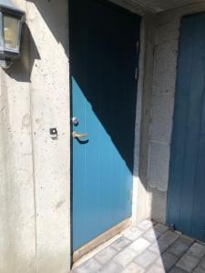 una puerta azul en el lateral de un edificio en Koselig nyoppusset 3 roms leilighet med egen parkeringsplass i rolige omgivelse nær sjøen, 2 mil nord for Bergen sentrum., en Bergen