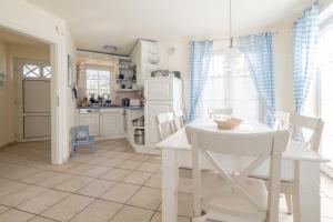 a white kitchen with a white table and chairs at Haus Möwe in Zingst