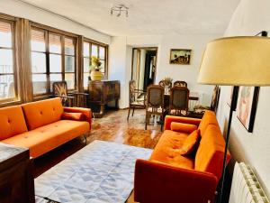 a living room with orange couches and a table at Casa Santa María 2 con jardín y barbacoa in Arévalo