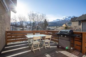 a grill on a deck with a table and chairs at Le Brec in Barcelonnette