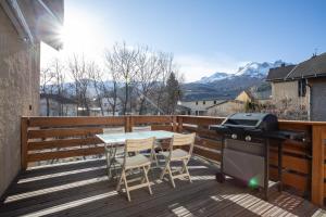 un grill su una terrazza con tavolo e sedie di Le Brec a Barcelonnette