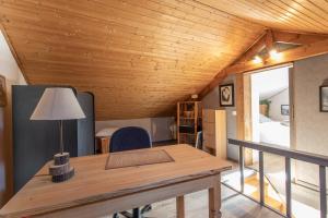 a room with a wooden ceiling and a table with a lamp at Le Brec in Barcelonnette