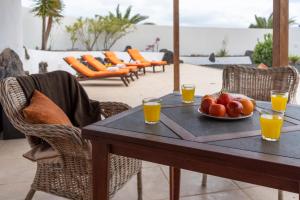 une table avec une assiette de fruits et des verres de jus d'orange dans l'établissement Casa Monicha, à Costa Teguise