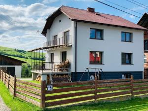 a white house with a wooden fence at Dom, Apartamenty, Agroturystyka in Kacwin