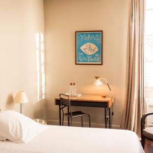 a bedroom with a desk and a bed and a desk with a table at Grand Hôtel Nord-Pinus in Arles