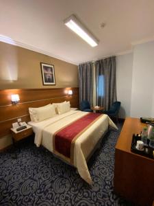 a hotel room with a large bed and a desk at Saraya Harmony Hotel B in Al Madinah