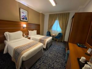 a hotel room with two beds and a table at Saraya Harmony Hotel B in Al Madinah