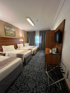 a hotel room with three beds and a flat screen tv at Saraya Harmony Hotel B in Al Madinah