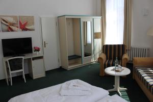 ツィノヴィッツにあるBaltisches Haus Pension Mollのベッド、ソファ、テレビが備わるホテルルームです。