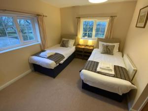 two beds in a room with two windows at Magnolia Cottage in Launceston