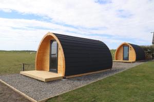 two small cottages sitting on top of a field at Kirkapol Beach Pod - Ebb in Middleton