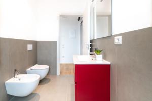 a bathroom with a white toilet and a red cabinet at Superior Beach Aparthotel in Lido di Jesolo