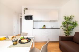 a kitchen with white cabinets and a plate of food on a table at Superior Beach Aparthotel in Lido di Jesolo