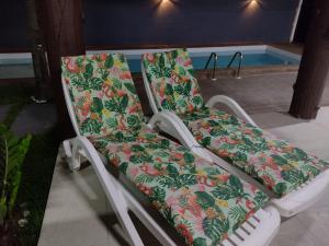 un paio di sedie sedute accanto alla piscina di Casa encantadora com piscina prainha e SPA a João Pessoa