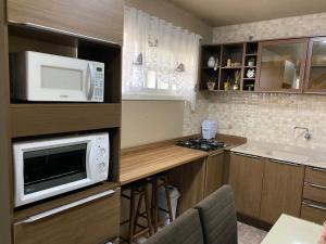 a small kitchen with a microwave and a counter at Apartamento Catedral Canela in Canela