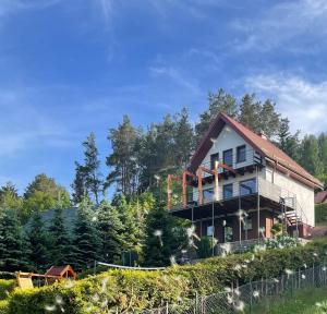 uma casa no topo de uma colina com árvores em Wakacyjny Hartowiec - dom nad brzegiem jeziora em Grodziczno