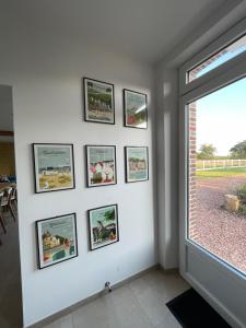 a wall with framed pictures on a wall with a window at La Maison des Jonquerets in Jonquerets-de-Livet