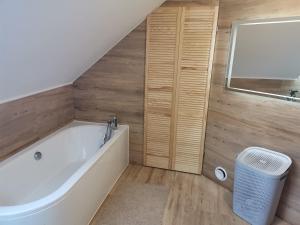 a bathroom with a white tub and wooden walls at Dom nad jeziorem - MAZURY in Szczytno