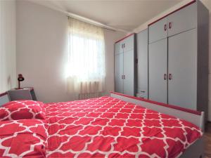 a bedroom with a red and white bed and a window at Apartments Morena in Rakalj