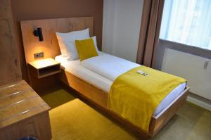 a bedroom with a bed with a yellow blanket at Hotel Am Markt in Karlsruhe