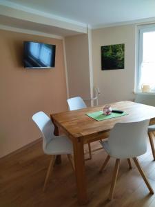 uma sala de jantar com uma mesa de madeira e cadeiras brancas em Ferienwohnung Kreuzgasse em Bad Frankenhausen