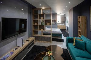 ein Wohnzimmer mit einem Sofa, einem TV und einem Bett in der Unterkunft LP Apartments in Tuzla