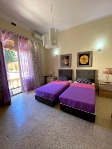 two beds in a large room with purple sheets at Magical Casalgo House in Victoria