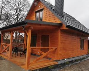 a large wooden cabin with a table on a deck at Domek Marcel Roztocze in Krasnobród
