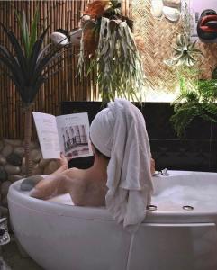 a man sitting in a bath tub reading a book at Fas BnB in Jiali